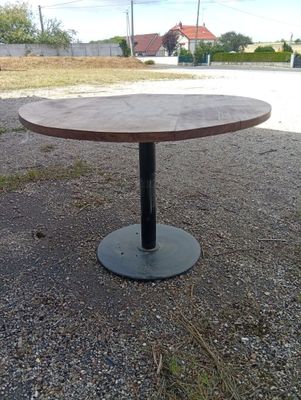 a round table with a metal base in the middle of a gravel road