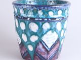 a blue pot with a pattern on it on a white surface