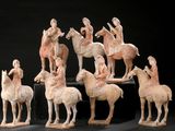 several figurines of people riding horses and horses on a black surface