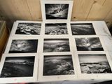 Plusieurs photographies en noir et blanc représentant une chaîne de montagnes sont disposées sur une table