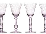 four wine glasses are lined up in a row on a white surface