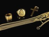 trois anneaux en or et une chaîne ornée d'une croix sur fond noir