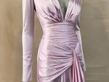 Le mannequin porte une robe rose à manches longues.