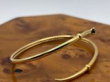 un gros plan sur une paire de boucles d'oreilles créoles en or posées sur une planche en bois