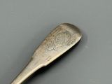 une cuillère en argent ornée d'un motif, posée sur une table