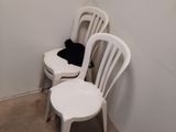 three white plastic chairs in a corner of a room