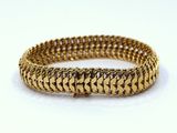 a close up of a gold bracelet on a white surface