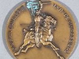 a gold medal with a man on a horse holding a flag
