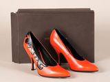 une paire de chaussures à talons hauts orange et noires posées devant une boîte