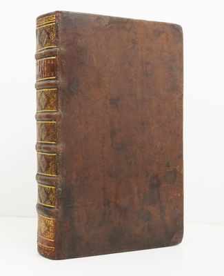 un vieux livre à la couverture en cuir marron posé sur une surface blanche