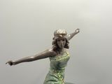 statue d'une femme en robe verte, les bras tendus