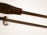 paire de couteaux anciens en bois et en métal posés sur une surface blanche