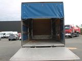 a truck that is parked in a lot with a blue tarp on the back of it