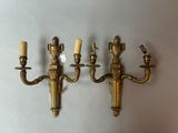 three antique brass wall sconces with candles on a white background