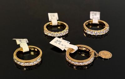 three gold rings with diamonds on a black surface with a price tag