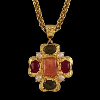 une photo d'un collier en or orné d'une pierre rouge et de perles