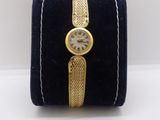 an image of a gold wrist watch with a blue velvet case