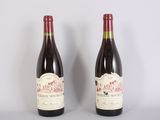 two bottles of red wine sitting next to each other on a table