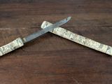 two knives on a wooden table with a piece of wood