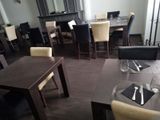 tables and chairs in a restaurant with a fireplace in the background