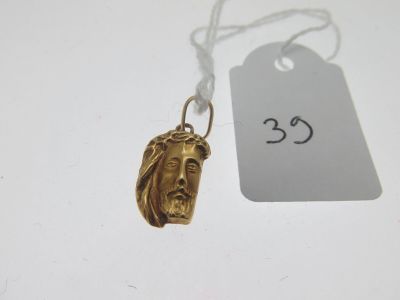 un gros plan sur un collier en or orné d'un visage de Jésus
