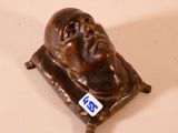 une statue représentant un homme assis sur un coussin posé sur une table