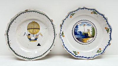 deux assiettes avec une montgolfière peinte dessus, posées sur une table