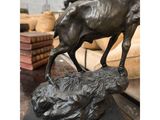 bronze statue of a goat on a rock in a warehouse