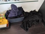 une valise noire sur laquelle est posée une serviette violette, à côté d'une pile de livres
