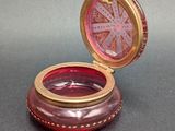 purple glass box with a gold rim and a pink glass lid