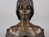a bronze bust of a woman with a flower in her hair
