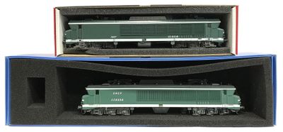 deux trains miniatures posés dans une boîte sur une surface blanche