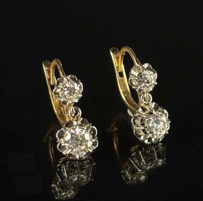 pair of diamond earrings on black surface with reflection