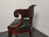 an old wooden chair with green leather seat in a corner