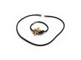 un collier à cordon noir orné d'une breloque en forme d'abeille dorée sur fond blanc