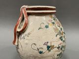 a white vase with a red handle on a gray surface