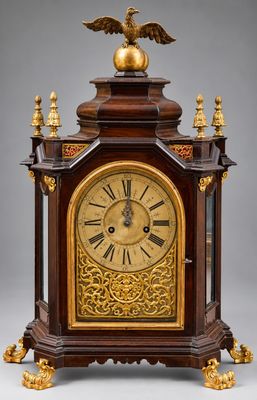 une vieille horloge en bois surmontée d'un aigle royal