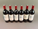 six bottles of red wine lined up in a row on a table