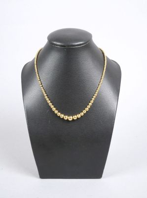 un collier avec une boule en or autour du cou d'un mannequin, sur fond blanc