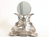 un miroir argenté en forme de papillon posé sur un socle, avec un miroir au centre