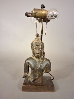a statue of a person sitting on a table with a lamp on it
