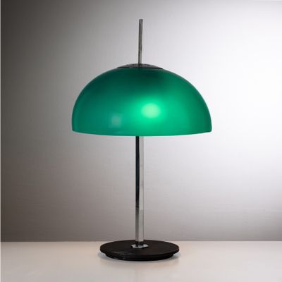 la lampe verte repose sur un socle noir posé sur une table blanche