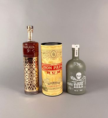 trois bouteilles d'alcool et une bonbonne posées sur une table
