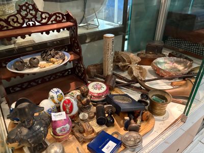 une vitrine remplie d'objets anciens, derrière une paroi en verre