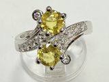 un gros plan d'une bague sertie d'un diamant jaune et blanc posée sur une surface transparente