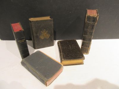 Plusieurs vieux livres sont posés les uns à côté des autres sur une surface blanche.