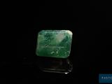 une photo d'un morceau de jade vert posé sur une surface noire