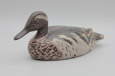 un canard en bois posé sur une surface blanche