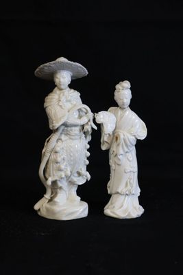 paire de figurines en porcelaine blanche représentant une femme et un homme avec une ombrelle