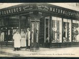 une vieille photo en noir et blanc montrant deux hommes et une femme debout devant un magasin